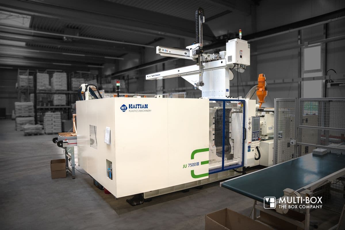 View of a modern injection molding machine for industrial housings in a production hall.