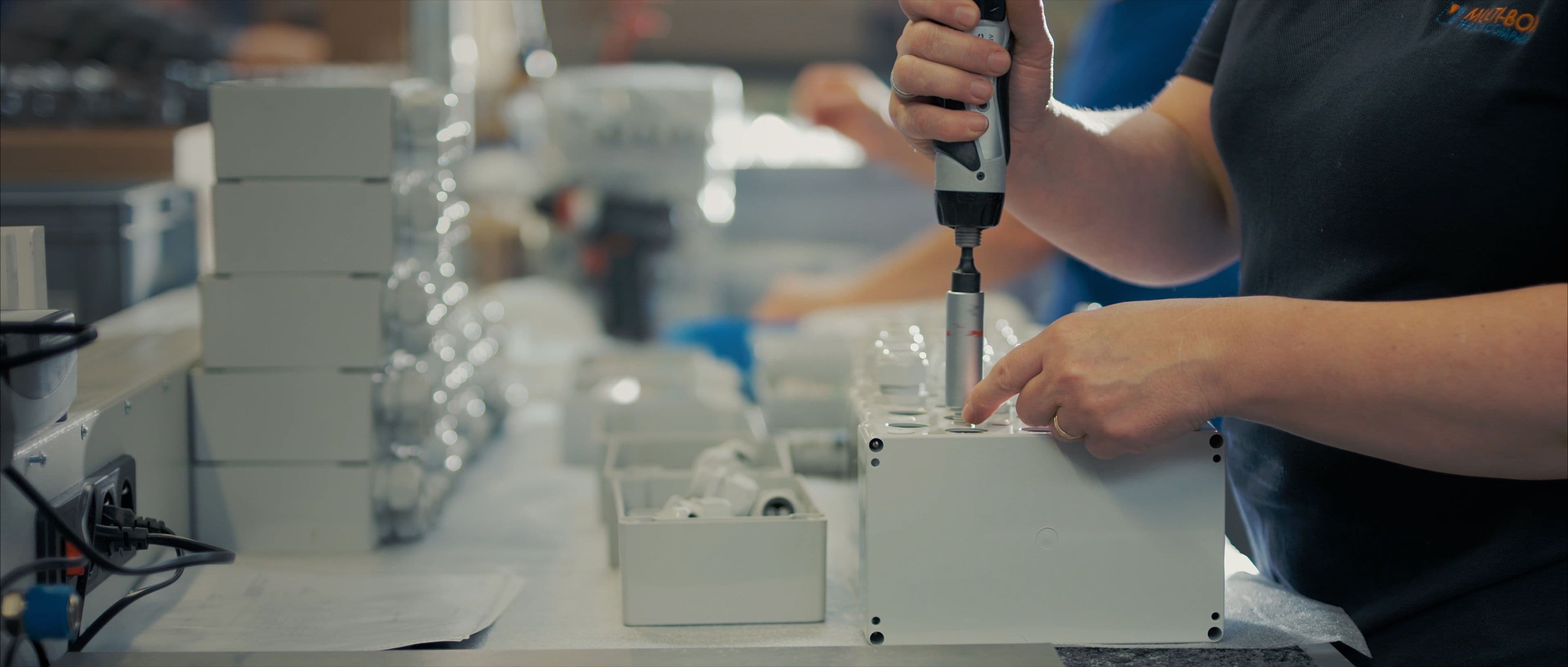 Nahaufnahme eines Mitarbeiters der mittels eines Elektroschraubers ein Gehäuse in der Produktion bei MULTI-BOX montiert.