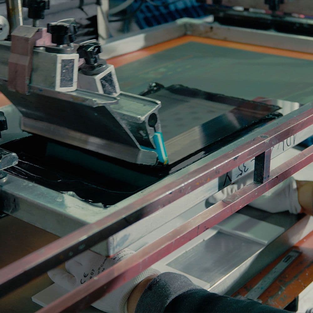 A technician inspects a metal enclosure with precisely drilled holes using a measuring tool.