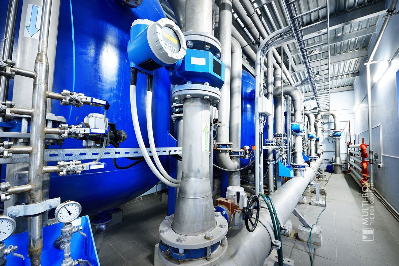 An industrial facility with blue tanks, pipes, and valves, showing a complex pipeline structure.