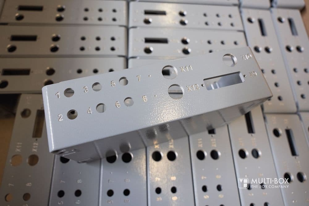 A gray aluminum enclosure with multiple drillings and engravings, prepared for industrial applications.