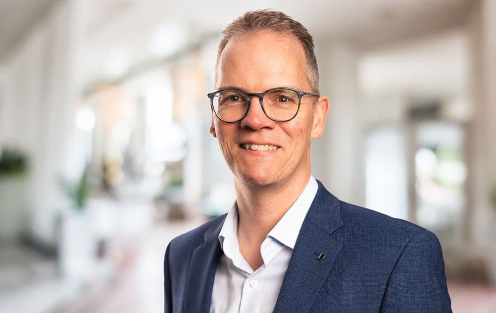 Freundliches Porträt von Markus Wilde, Ansprechpartner im Außendienst. Lächelnder Mann im Anzug, in einem modernen Büroambiente.